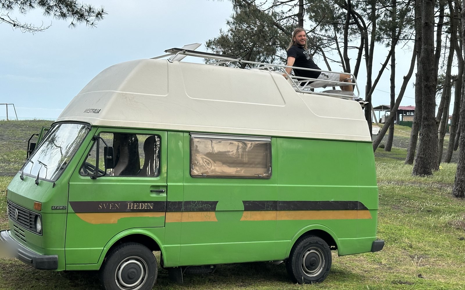 Green VW LT28 Westfalia campervan parked by the sea